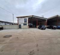 Ipari épület a Strojnícka utcában, Eperjesen, parkolóhelyekkel és autókkal.