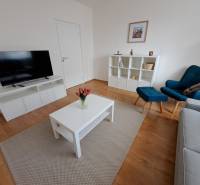 Nappali egy háromszobás lakásban, fa dekoros padlóval és egyszerű bútorokkal.