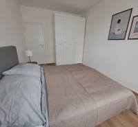 Hálószoba egy háromszobás lakásban ággyal, szekrénnyel és fa dekorú padlóval.