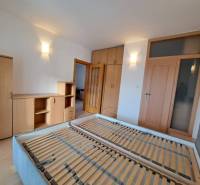 Hálószoba egy 4 szobás lakásban fa dekorációjú bútorokkal és matrac nélküli ággyal.