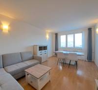 Nappali egy 4 szobás lakásban, fa dekoros padlóval és szürke kanapéval.