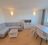 Nappali egy négy szobás lakásban sarokkanapéval és étkezőasztallal.