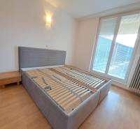 Hálószoba egy 4 szobás lakásban ággyal és éjjeliszekrénnyel, fa dekoros padlóval.