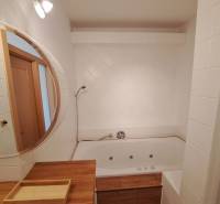 Fürdőszoba tükörrel és káddal egy 4 szobás lakásban; fa dekoráció használata.