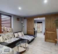 Nappali kényelmes kanapéval, tolóajtókkal és fa dekorációjú padlóval.