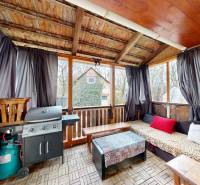 A családi házban van egy fedett terasz grillel, szélfogóval és kerti bútorokkal.