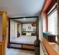 Hálószoba családi házban nagy ággyal és függő növénnyel az ablak mellett.