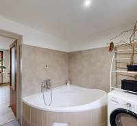 Fürdőszoba családi házban sarokkáddal, mosógéppel és virágokkal.