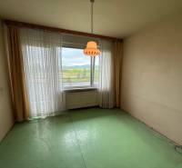 Szoba zöld padlóval és nagy ablakkal egy háromszobás lakásban.