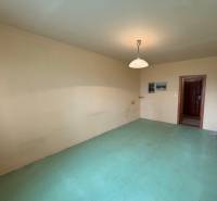 Szoba egy háromszobás lakásban semleges falakkal és világos padlóburkolattal.