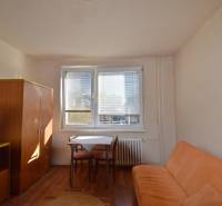 Studiolakas kanapéval, asztallal és szekrénnyel, fa dekoros padlóval.