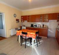 Konyha egy családi házban fa dekorációval és narancssárga terítővel az asztalon.