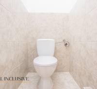 Világos csempékkel burkolt WC egy épületben.