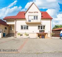 Piros tetős épület és kijelölt parkoló Dunaszerdahelyen.