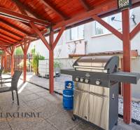 Pavilon Dunaszerdahelyen grillel és kerti bútorokkal, kavicsos ágy.