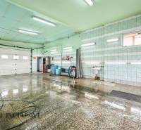 Egy helyiség az épületben nedves csempével, mosdóval és egy tömlővel a falon.