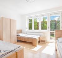 Világos szoba három ággyal, fehér falakkal, szekrényekkel és nagy ablakokkal.