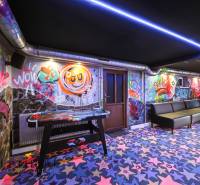 Az épület belseje graffiti-vel a falakon, színes szőnyegekkel és asztali hokival.