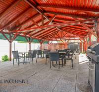 A Dunaszerdahelyi épület kültéri terasza fa tetővel és grillel.