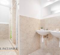 Két mosdókagylós és zuhanyzós fürdőszoba, dekoratív csempék és tükör az épületben.