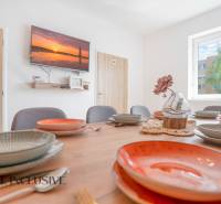 Ebédlő egy épületben dekoratív asztallal, színes tányérokkal és falra szerelt televízióval.