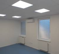 Irodák fehér mennyezettel, kék padlóval és redőnyös ablakokkal.