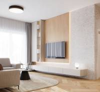 Nappali egy 4 szobás lakásban, fa dekoros padlóval, világos kanapéval és falra szerelt TV-vel.