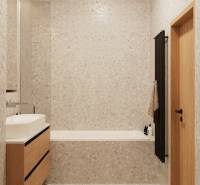 Fürdőszoba világos csempével, fa mosdószekrénnyel és sötét létra radiátorral.