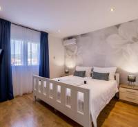 Világos hálószoba TV-vel, légkondicionálóval és fa dekorációjú padlóval a villában.