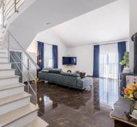 Nappali egy villában fényes padlóval és kék függönyökkel.