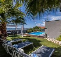 Hangulatos kert medencével egy kastélyban Kaštelában, pálmafákkal és napozóágyakkal körülvéve.