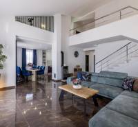 Nappali egy villában kényelmes kanapéval, étkezővel és lépcsővel, fa dekorációjú padlóval.