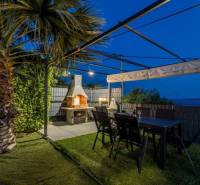 A Kaštela-i villa pálmakertje pergolával, kandallóval és asztallal.