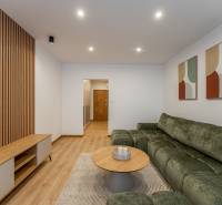 Nappali egy kétszobás lakásban kanapéval, asztallal és fa dekorációjú padlóval.