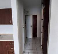 Konyha sötét szekrényekkel és fehér csempékkel egy egyszobás lakásban.