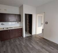 Konyha sötét szekrényekkel és fa dekorációjú padlóval egy egyszobás lakásban.