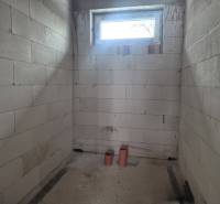 Vakolatlan falak, kis ablak és PVC csövek a családi házban.