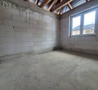 Betonpadló, festetlen téglák és fa gerendák a családi ház belsejében.