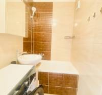 Fürdőszoba egy kétszobás lakásban mosdóval, káddal és mosógéppel.