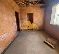 Egy építés alatt álló családi ház belső tere, látható téglákkal és építőanyagokkal.