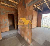 Félkész családi ház vakolatlan falakkal és fa tetőszerkezettel.