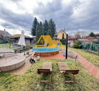 Kert a ház mellett medencével az utcán Érsekújváron, gondozott zölddel körülvéve.