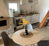 Egy faház belseje asztallal, négy székkel és konyhasarokkal, fa dekorációjú padlóval.