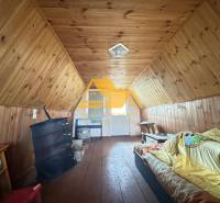 Faház tetőtér fa dekorációval és egyszerű berendezéssel, kellemes pihenőhely.