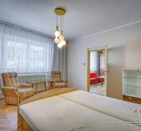 Családi ház hálószobája világos fa bútorokkal és kényelmes fotelekkel.