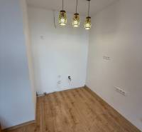 1 szobás lakás belső tere fa mintázatú padlóval és függő világítótestekkel.