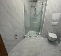 Fürdőszoba márvány burkolattal és zuhanyzóval egy egyszobás lakásban.