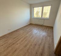 Szoba egy kétszobás lakásban, fa dekorációjú padlóval és nagy ablakkal.