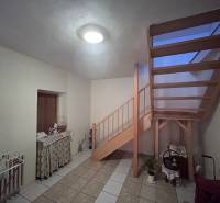 Családi ház belső tere fa lépcsővel, asztallal és kerámia csempével burkolt padlóval.