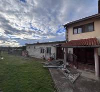 Családi ház Zbehyben gyepes udvarral, kerttel és kövezett sétánnyal a felhős ég alatt.